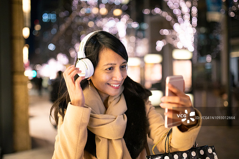 亚洲女人冬夜戴耳机听音乐图片素材