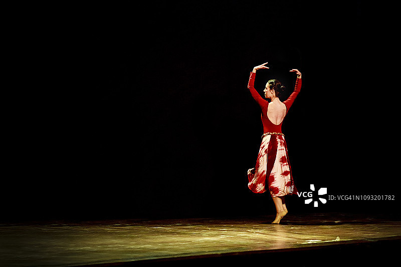 在黑色背景的空旷舞台上跳芭蕾舞的女人图片素材