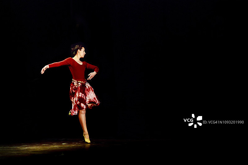 在黑色背景的空旷舞台上跳芭蕾舞的女人图片素材