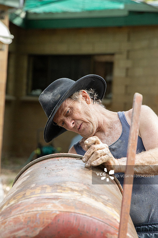 自制砖块用于房屋建造，男子在混凝土搅拌机中准备砖块混合物图片素材