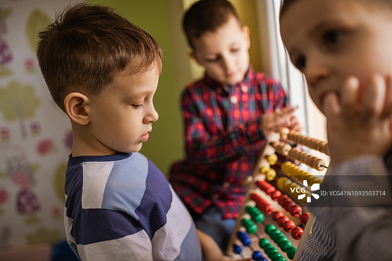 幼儿园里用算盘数数的小男孩们图片素材
