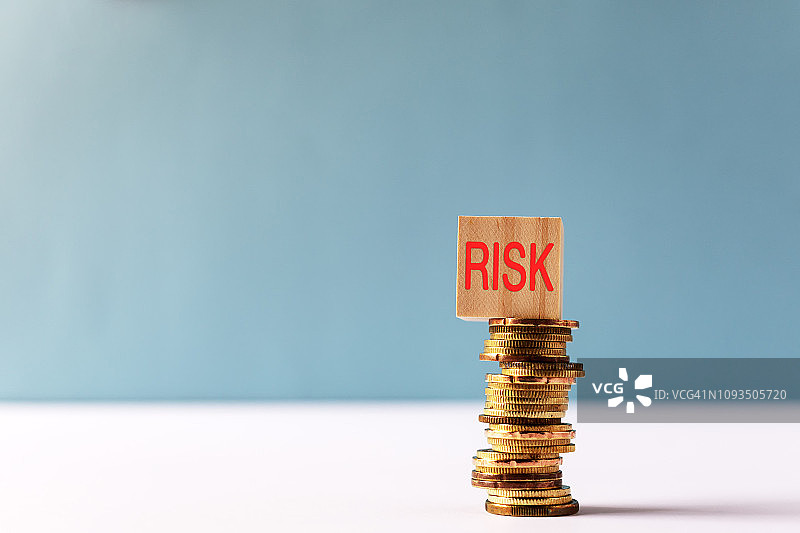 带有“风险”字样的木块在硬币堆顶部图片素材