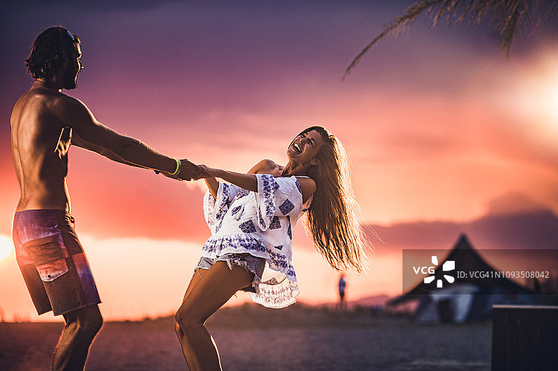 年轻情侣在日落时分的沙滩上旋转图片素材