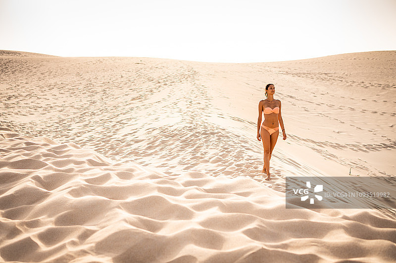 在沙丘上行走的美丽女人图片素材
