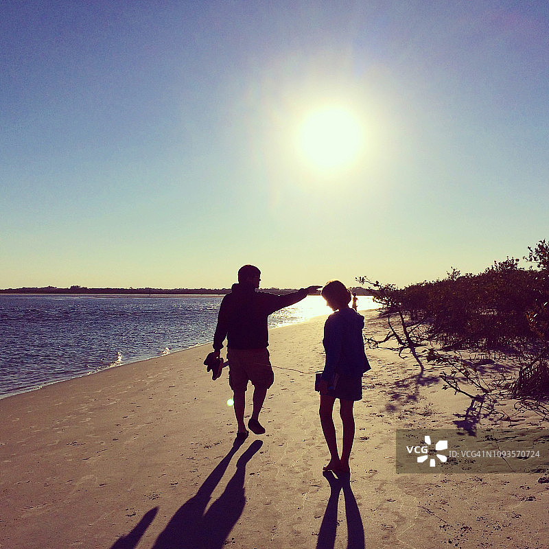父女在日落时分的海滩上散步图片素材
