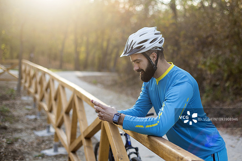 年轻的自行车手在手机上发短信图片素材