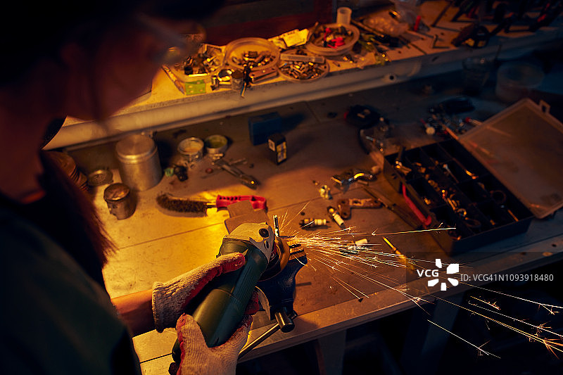 在车间切割金属零件的年轻女人图片素材