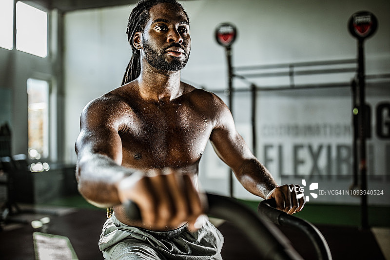 在健身房里骑健身单车的非裔美国健壮男子图片素材