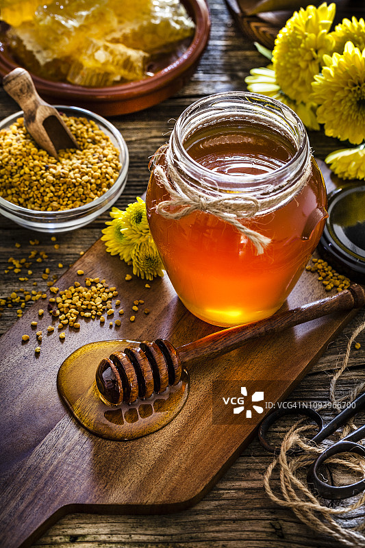 乡村木桌上的蜂蜜罐、蜂花粉和蜂巢图片素材