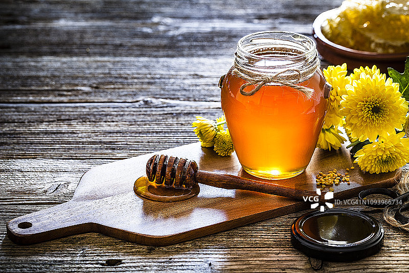乡村木桌上的蜂蜜罐和蜂蜜勺图片素材