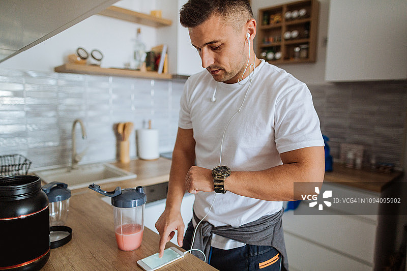 年轻男人将智能手机应用程序与智能穿戴设备同步图片素材