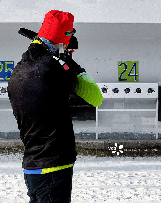 年轻男子参加冬季两项比赛，练习目标射击（焦点堆叠后视图）图片素材