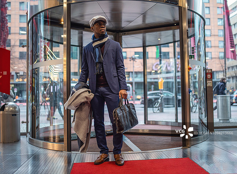 英俊的企业家通过旋转门进入购物中心图片素材