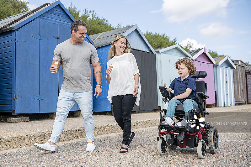 父母微笑看着坐在轮椅上的儿子图片素材