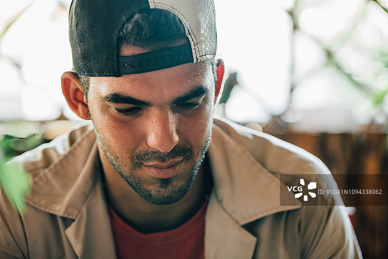 戴棒球帽向下看的年轻男人图片素材