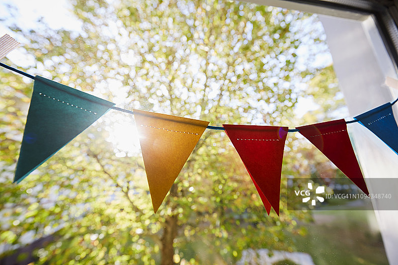 窗户上悬挂的彩色彩旗/派对装饰的三角旗链图片素材