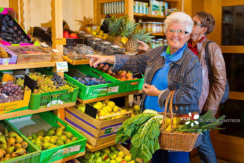 在食品店对着镜头微笑的快乐70岁女人图片素材