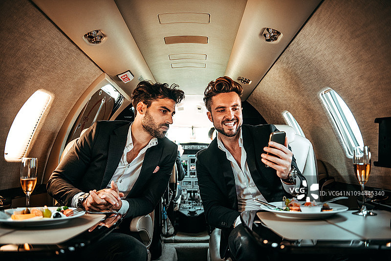 两名经理在私人飞机上用餐时一起看手机图片素材