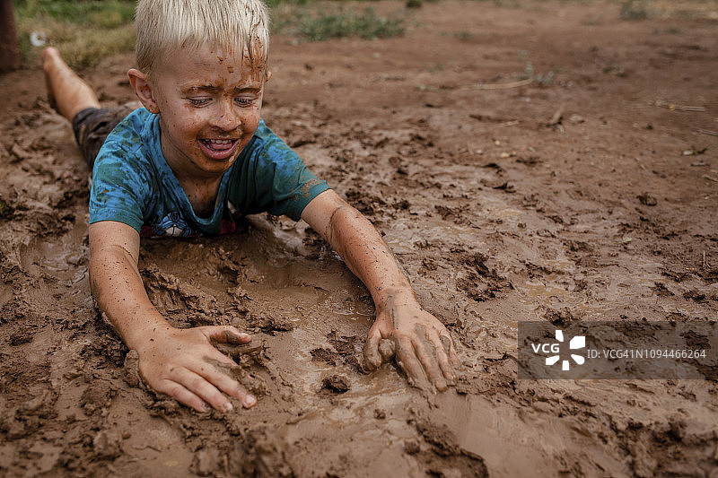 庭院泥泞地上玩耍的男孩高角度视图图片素材