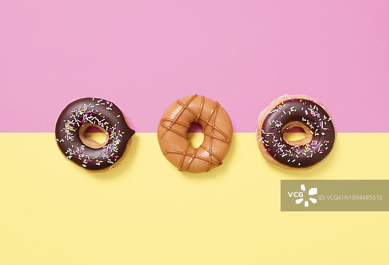 彩色背景上排列的甜甜圈俯视图图片素材
