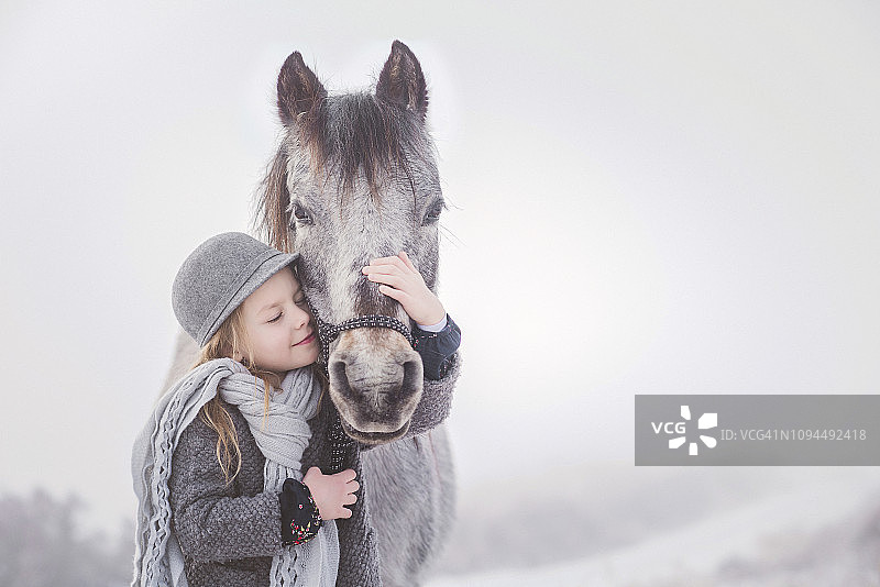 冬天里，可爱的女孩拥抱小马图片素材