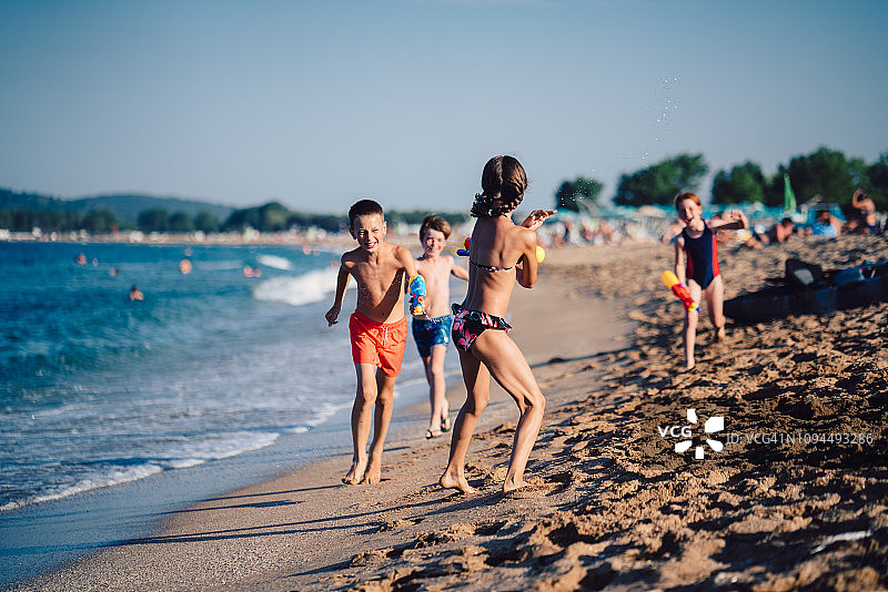 孩子们在海滩上用水枪奔跑和射击图片素材