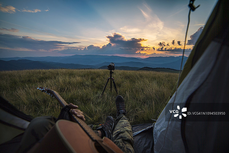 日落时分，男子在山间帐篷里弹吉他图片素材
