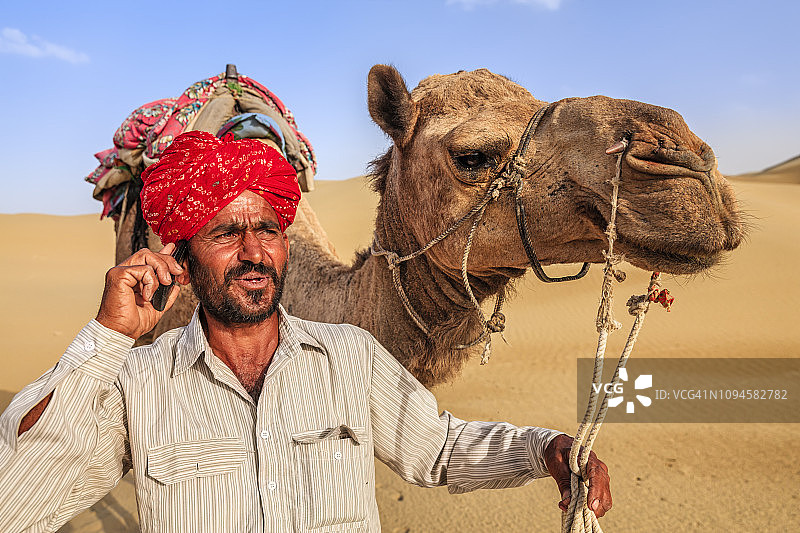 在印度沙漠村庄使用手机的印度男子图片素材