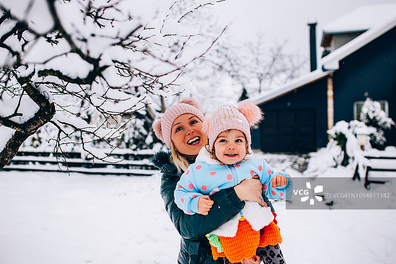 快乐的母亲在雪地里和宝宝玩耍图片素材