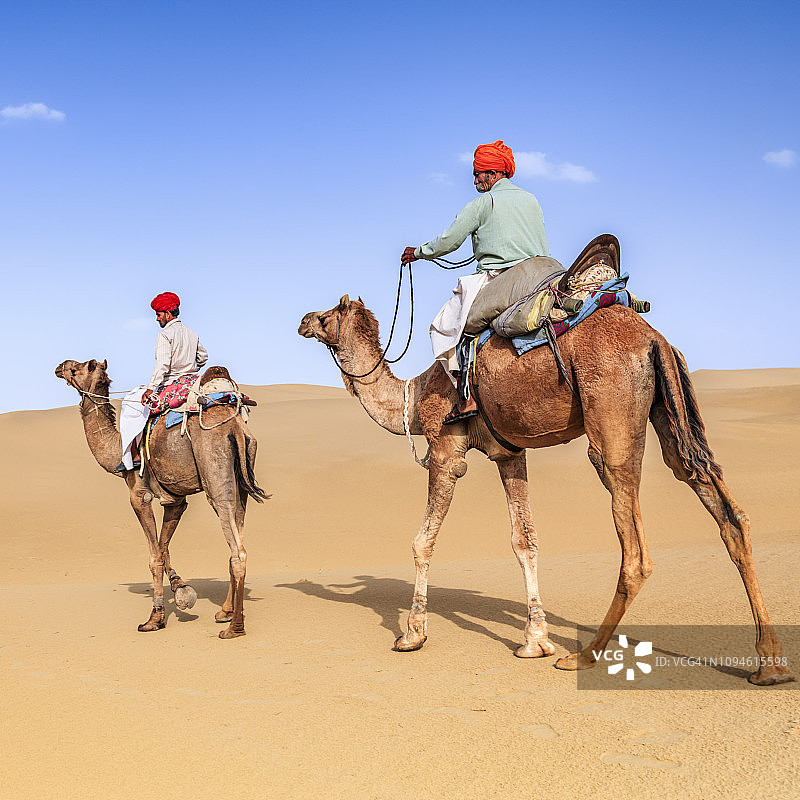 印度拉贾斯坦邦，骑着骆驼在沙丘上的人图片素材