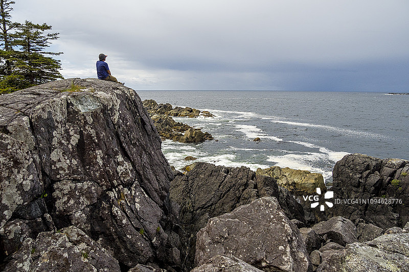 男子坐在加拿大不列颠哥伦比亚省托菲诺温泉湾海岸的岩石上图片素材