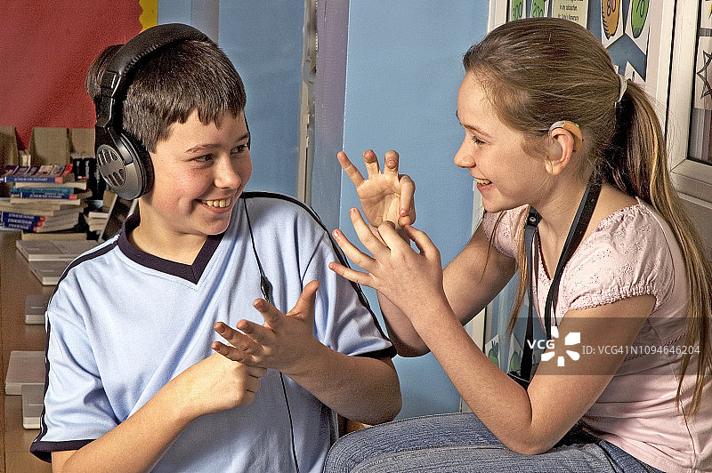 在教室里使用手语的佩戴助听器的聋儿图片素材