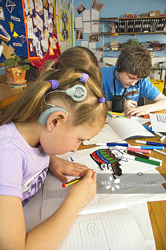 课堂上使用手语交流的佩戴助听器的失聪儿童图片素材