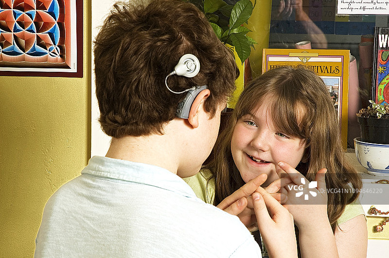 在教室里使用手语的佩戴助听器的聋儿图片素材