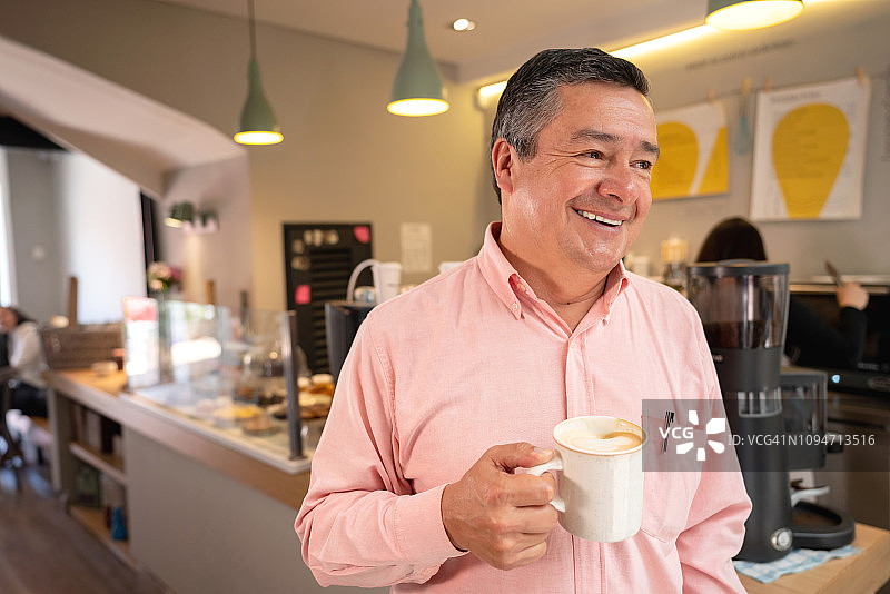 快乐的拉丁美洲男人在咖啡店喝卡布奇诺图片素材