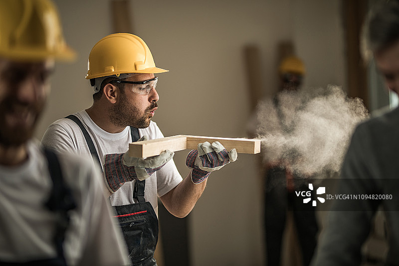 工人在建筑工地吹掉木板上的锯末图片素材