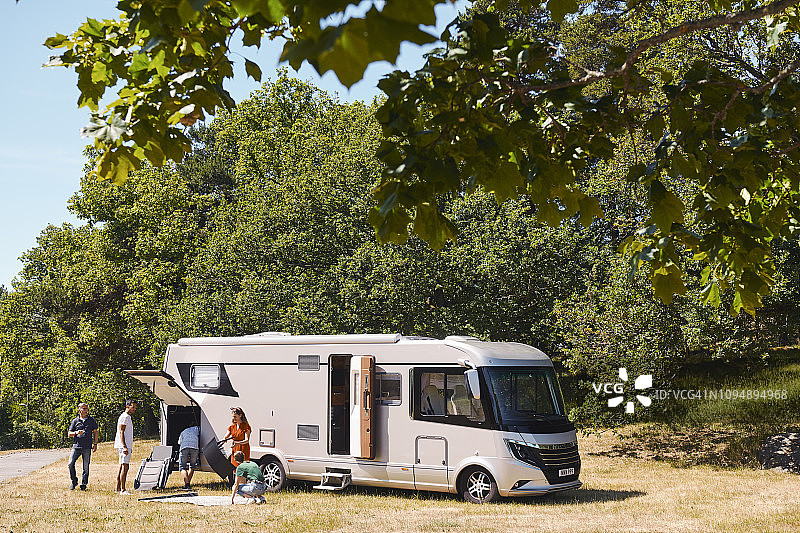 家庭在拖车公园卸下停靠在树旁的房车图片素材