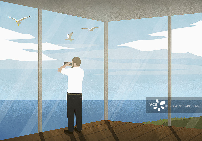 男子在海滩别墅用双筒望远镜欣赏海景图片素材