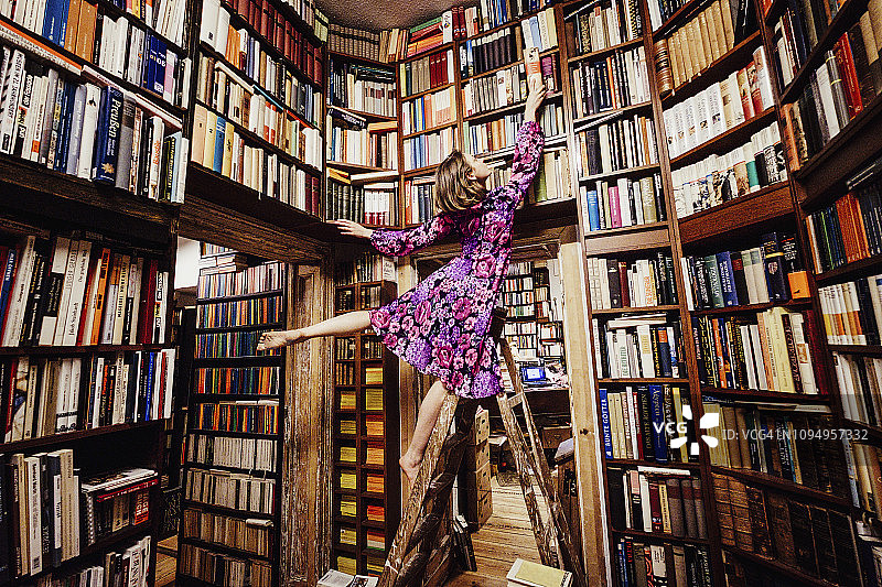 在图书馆梯子上取书的无忧女人图片素材