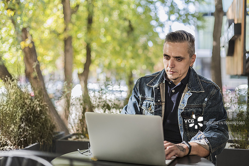 在路边咖啡馆使用笔记本电脑的男人图片素材