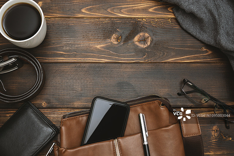 男士斜挎包、手机和个人物品（乡村木质背景）图片素材