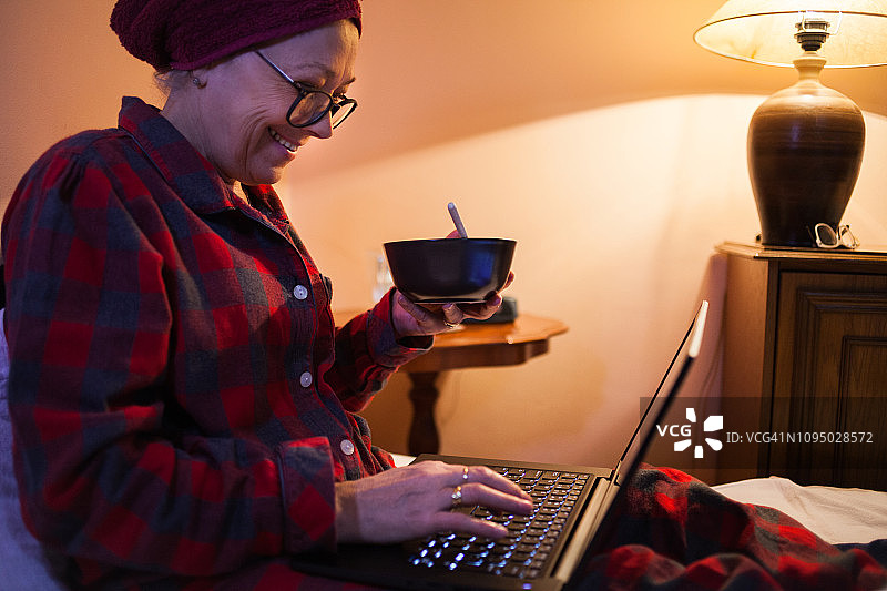 在床上使用笔记本电脑的老年妇女图片素材