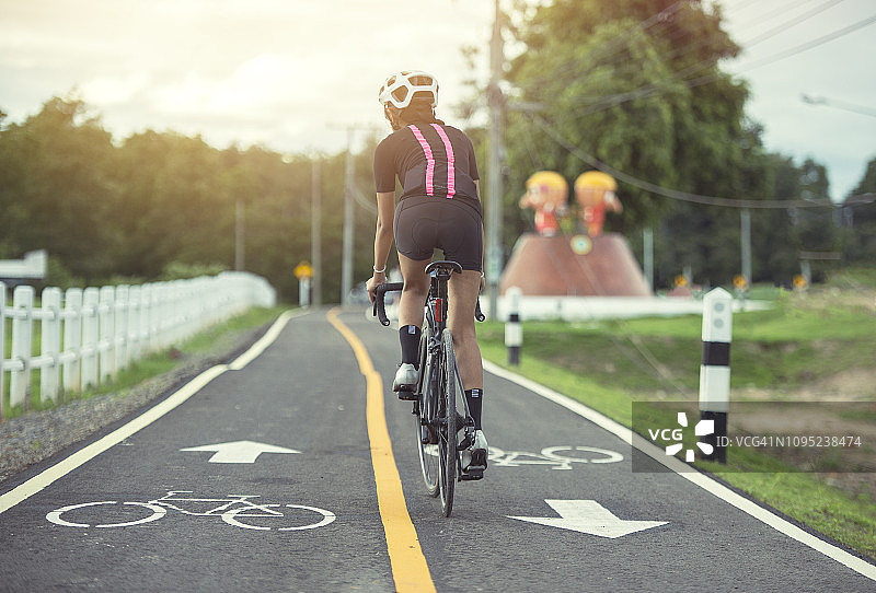 戴头盔的亚洲健康女孩在自行车道上骑行锻炼图片素材