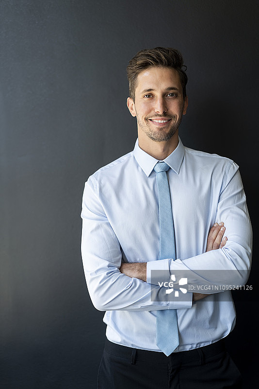 商人双手交叉靠墙站立图片素材