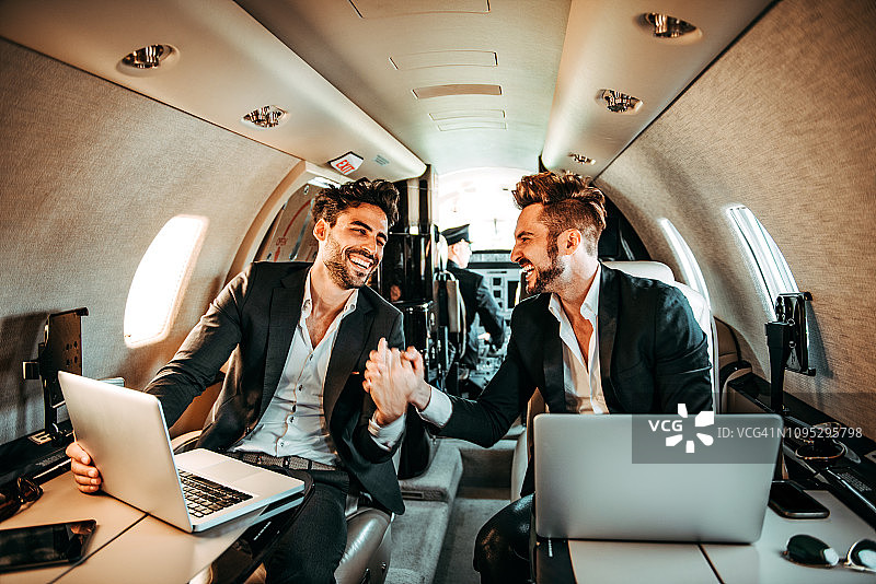 两个富商在私人飞机上商务旅行时握手图片素材