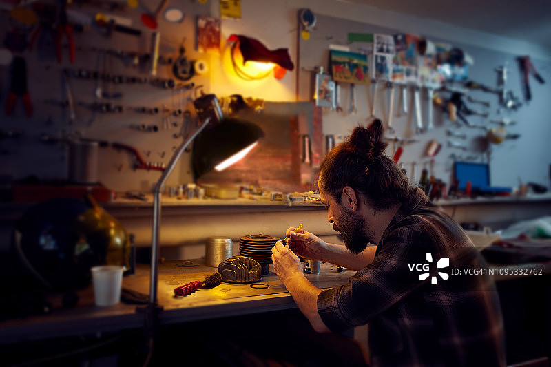 年轻男子在车间清洁摩托车活塞图片素材