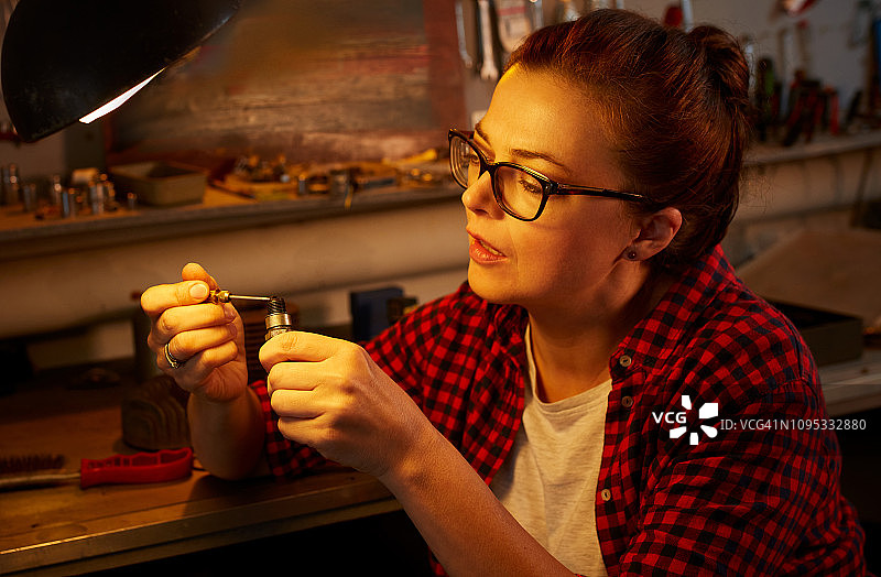 在车间检查摩托车火花塞的女人图片素材