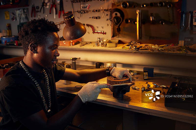 在车间清洁摩托车气缸的非洲男子图片素材