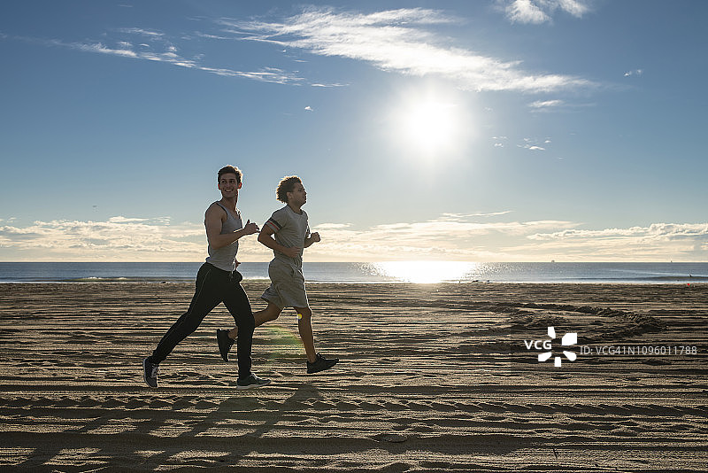在海滩慢跑的两个年轻朋友图片素材
