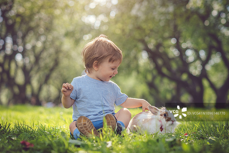 可爱的小男孩在复活节彩蛋寻宝活动中与兔子玩耍图片素材
